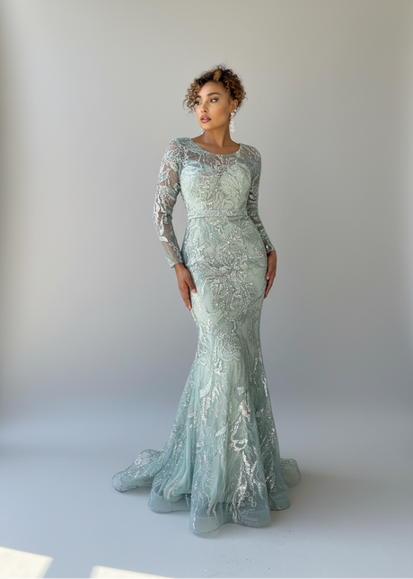 A model wearing a full-length formal gown with lace applique detailing and sequins, featuring a round neckline and long sleeves, in a mermaid style.