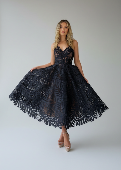 A woman wearing a green midi length strapless dress with lace detailing and a sweetheart neckline.